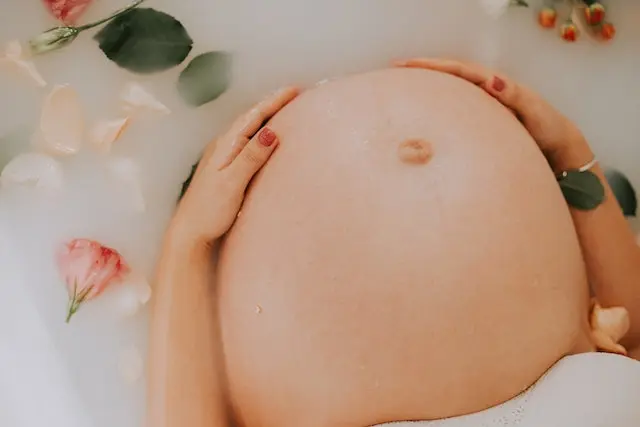 Un femme enceinte dans un bain de lait avec des fleurs